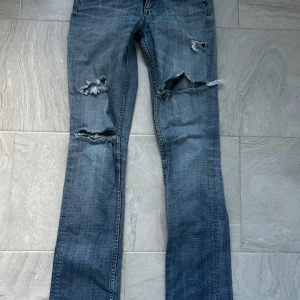 Blå lowwaist jeans med slitningar - Jeans i lowwaist modell med slitningar på framsidan.