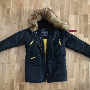 Svart parkajacka från Alpha Industries - Säljer en svart parkajacka från Alpha Industries i storlek Small. Jackan har en mysig pälsfodrad huva och flera praktiska fickor med dragkedja. Perfekt för kalla vinterdagar! 🧥❄️