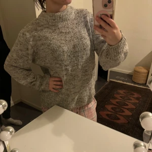 Grå stickad tröja - Mysig grå stickad tröja perfekt för kyliga dagar. Den har en avslappnad passform med långa ärmar och en hög krage som håller dig varm. Tröjan är i ett melerat mönster som ger en stilren look. Perfekt för både vardag och mysiga hemmakvällar. strl xl men se bild passar utmärkt på xs/s❤️