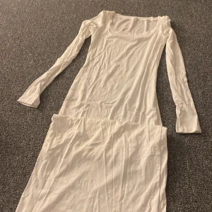 Vit långklänning - Säljer en elegant vit långklänning med långa ärmar. Perfekt för sommarens fester eller en stilren look till vardags. Klänningen har en enkel och klassisk design som passar till många tillfällen.