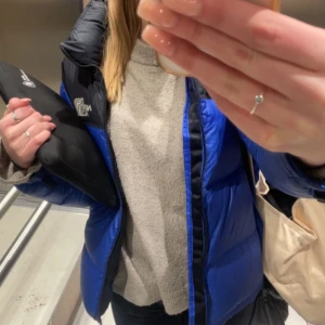 Blå och svart dunjacka från The North Face - Säljer en snygg blå och svart dunjacka från The North Face. Jackan har en dragkedja framtill och fickor på sidorna samt en innerficka med dragkedja. Jackan är väldigt varm vilket är perfekt till vinter!!