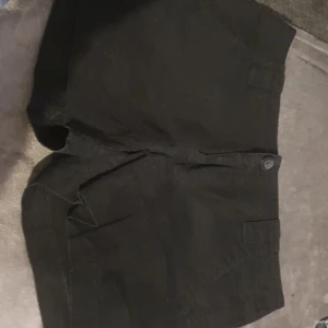 Svarta shorts med fickor - Säljer ett par svarta shorts i bra skick. De har praktiska fickor och en knapp framtill. Perfekta för sommaren eller en avslappnad dag ute. Passar till det mesta och är superbekväma!