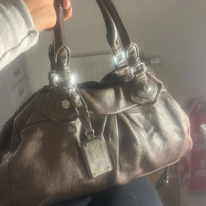 Säljer min Marc Jacobs väska eftersom att jag vill köpa en mindre version - Väskan är väl använd men i mycket bra skick. Väskan har en praktisk axelrem och fina detaljer med spännen och en metallbricka framtill. Perfekt för både vardag och fest. Väskan är väldigt rymlig. Jag får plats med alla skolsaker som dator i. Pris går att diskuteras!❤️Bara hör av dig om du har fler frågor eller vill ha fler bilder ❤️