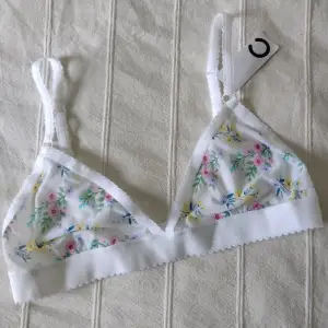 Säljer en superfin vit bralette med blommigt mönster. Den är i nytt skick och har justerbara axelband för perfekt passform 🌸