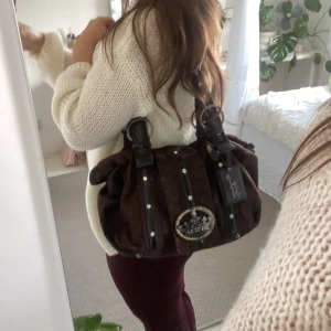 jätte fin brun axelväska !🤎 - Säljer en snygg brun axelväska från Friss & Company, liknar juicy culture! Väskan har dekorativa detaljer med nitar och en stor krona emblem framtill. Den är i mycket bra skick och perfekt för höst och vinter🤎🪽