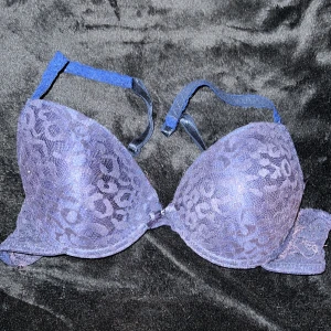 Blå spets-bh 75B - Säljer en blå bh i storlek 75B. Den har ett snyggt leopardmönster i spets och justerbara axelband. Bh:n är i bra skick, men det hänger ut lite elastiska trådar här och där men inget som stör funktionen, bara att klippa bort. 