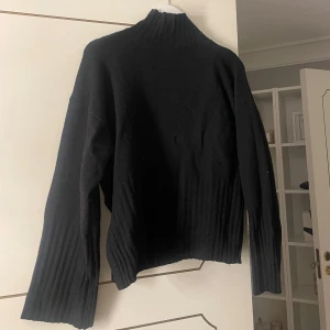 Svart stickad tröja - Säljer en stilren svart stickad tröja med hög krage. Perfekt för kyliga dagar med sin mysiga och varma känsla. 