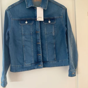 Blå jeansjacka från Zadig & Voltaire - Säljer en snygg blå  jeansjacka från Zadig & Voltaire i nyskick. Jackan har coola broderier på ryggen med blommor och dödskallar. Den har långa ärmar och knappar framtill. Perfekt för vår och höst!