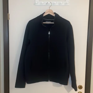 Mörkblå tröja  från Tommy Hilfiger - Säljer en stilren blå tröja från Tommy Hilfiger i vintage fit. Tröjan har en dragkedja framtill och är långärmad. Perfekt för höst och vår, och den är i mycket bra skick. Passar både till vardags och lite finare tillfällen. Pris går alltid att förhandlas!