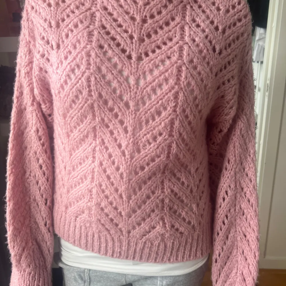 Superfin rosa stickad tröja med ett snyggt hålmönster. Perfekt för kyliga dagar när du vill vara både varm och stilren. Tröjan har långa ärmar och en bekväm passform. Ett måste i garderoben för höst och vinter!. Neuletakit & Villapaidat.