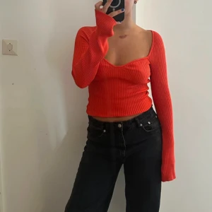 Röd ribbad croppad topp - Säljer en superfin röd ribbad topp med långa ärmar och en snygg croppad passform. Perfekt för både vardag och fest! Toppen har en djupare urringning som ger en extra touch. Passar perfekt till jeans eller kjol.