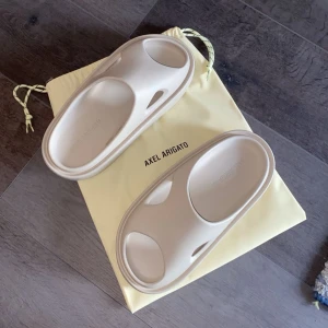 Axel arigato tofflor - Riktigt sköna axel arigato tofflor / slides i beige Storlek 42/43. Helt nya, Köptes literally 3 timmar sedan på deras sample sale i Göteborg  men passar tyvärr inte min fot så jag säljer de vidare. ☺️