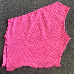 Rosa oneshoulder topp - Säljer en superfin rosa oneshoulder topp med slits på ena sidan material. Perfekt för sommaren eller en festkväll! Toppen har en asymmetrisk design som ger en unik look.