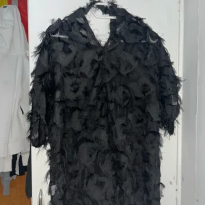 Svart blus från Shein - Säljer en unik svart blus från Shein i storlek 0XL. Den har en cool fransig design som ger en edgy look. Perfekt för en fest eller en utekväll! Blusen är i bra skick och redo att bäras.