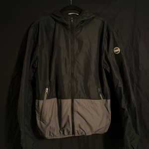 Svart vindjacka från Colmar - En svart vindjacka från Colmar Originals. Den är perfekt för vår och höst med sin lätta och smidiga design. Perfekt för en stilren look!