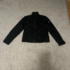 Svart Snoot jacka med dragkedja - Säljer en stilren svart jacka i mycket bra skick. Den har en dragkedja framtill och långa ärmar. Perfekt för höst och vår när du vill hålla det enkelt men snyggt. Jackan går att använda på båda sidorna. Jackan är i ett lätt material, vilket gör den bekväm att bära. Storleken är XS men passar även på en S. Använd ett få tal gånger, priset går alltid att diskutera😁