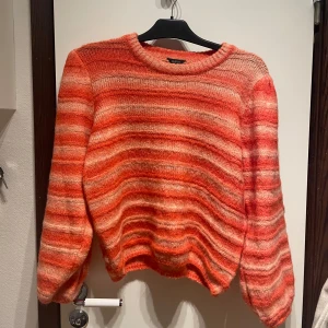 Orange stickad - En supermysig stickad, randig, tröja med puffiga armar. Tröjan är randig i orangeröda färger. Säljer pga att den inte används. Varan är i bra skick då den endast används ett fåtal gånger. 