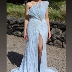 Catwalk festklänning - Säljer en jättefräsch ljusblå lång klänning med glittriga detaljer och en elegant slits. Klänningen är från catwalk och har endast används en kväll. Den kan användas till bal/bröllop/förlovning. Nypris 7000. Mitt pris 5500