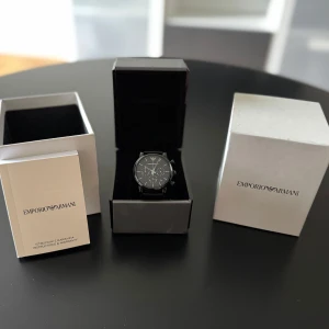 Emporio Armani Klocka - En klocka från Emporio Armani i modellen AR-1737. Klockan är i rostfritt stål och armbandet i krokodil-läder. Det finns lite slitage på armbandet efter användning men allt annat är i perfekt skick.