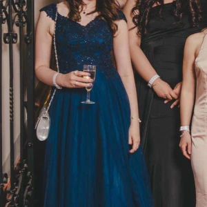 Blå långklänning med spetsdetaljer - Säljer en fantastisk blå långklänning med spetsdetaljer och en elegant v-ringning. Klänningen har en tight passform upptill och en flödande kjol som ger en vacker siluett. Perfekt för bal eller fest! 💙 inga defekter vad jag kan se och endast använd en gång. Storlek 40 och men passar mig som oftast har storlek 38. Skulle passa bäst med lite större byst än vad jag har. 