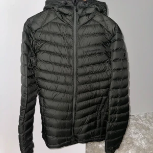 Grön dunjacka Peak Performance - Säljer en snygg grön dunjacka från Peak Performance i storlek S. Jackan är quiltad och har en dragkedja framtill. Perfekt för höst och vinter med sin varma och lätta design. Den har en huva och långa ärmar, vilket gör den idealisk för kyliga dagar. Passar både till vardags och utomhusaktiviteter. Endast använd ca 3-4 gånger förra året. (Nypris var ca 2800kr)