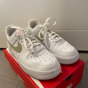 Nike Air Force 1 med rosa och gröna detaljer  - Säljer dessa Nike air force med rosa och gröna detaljer. Endast använda några få gånger, några fläckar kan finnas men fortfarande fina, hela och vita!