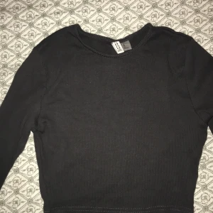 Grå ribbad tröja från H&M - Säljer en stilren grå ribbad tröja från H&M. Tröjan har långa ärmar och en rund halsringning, perfekt för lager på lager under kyligare dagar. Enkelt basplagg som passar till det mesta.