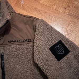 Beige fleecejacka från Maya Delorez - Säljer en fin beige fleecejacka från Maya Delorez. Jackan har en dragkedja framtill och svarta detaljer på ärmarna. Originalpris 1300kr💗 fint skick💗 storlek S