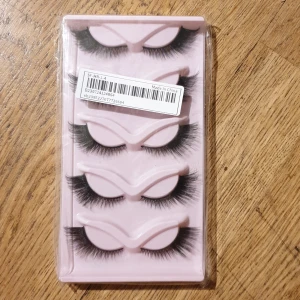 Svarta lösögonfransar i set - Set med fyra par svarta lösögonfransar. Fransarna är täta och dramatiska, perfekta för en intensiv look. De kommer i en rosa förpackning som håller dem säkra och organiserade.