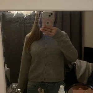 Grå kofta med knappar - Mysig grå kofta med knappar framtill. Perfekt för kyligare dagar och enkel att matcha med olika outfits.