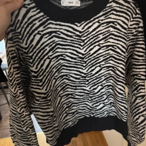 Zebramönstrad tröja från MNG - Säljer en cool zebramönstrad tröja från MNG i svart och vitt. Tröjan har långa ärmar och en rund halsringning med ribbade kanter. Perfekt för att sticka ut i mängden! 🦓
