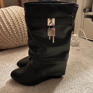 Svarta stövlar med låsdetalj/ Shark-boots  - Snygga svarta stövlar med en unik låsdetalj framtill. De har en rund tå och är tillverkade i ett syntetmaterial. Perfekta för att ge en edgy touch till din outfit.🫶🏼
