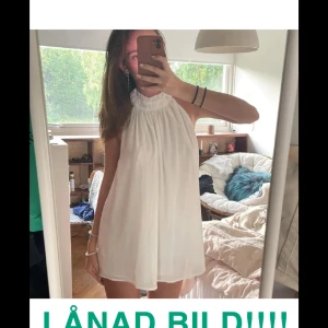 Vit ärmlös blus - Snygg vit ärmlös blus med hög hals och volangdetaljer. Perfekt för sommarens varma dagar. Lätt och luftig design som ger en elegant look. 