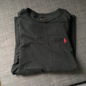 Svart långärmad tröja från Ralph Lauren - Säljer en stilren svart långärmad tröja från Ralph Lauren med det klassiska röda logotypen på bröstet.