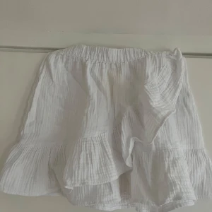 Vit kjol - Säljer en vit kjol från Gina young med volangdetaljer. De är tillverkade i ett lätt och luftigt material, perfekt för varma dagar. Shortsen har en elastisk midja för extra komfort. Perfekta för en somrig look! 🌞 Storlek 146/152 men passar xs/s💗