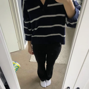 Mörkblå randig tröja - Säljer en mörkblå tröja med vita ränder och en v-ringad krage. Tröjan har en avslappnad passform med korta ärmar, perfekt för en casual look. Den är dock lite nopprig 💞