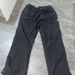 Svarta träningsbyxor från MPC - Säljer ett par svarta träningsbyxor från MPC. De har en elastisk midja med röd snörning för justerbar passform. Perfekta för träning eller avslappnade dagar även för att få den där baggy looken !! Byxorna går att stretcha ut jätte mycket!