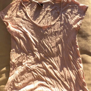 Rosa t-shirt från Gina Tricot - Säljer en enkel och stilren rosa t-shirt från Gina Tricot. Den har en rund halsringning och korta ärmar, perfekt för en avslappnad look. Passar bra till både jeans och kjol.