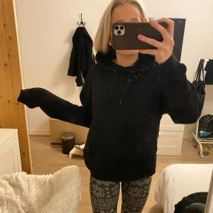 Svart hoodie - Säljer en svart hoodie med luva och dragsko. Perfekt för en avslappnad stil. Den har långa ärmar och en bekväm passform.