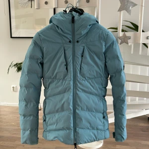 Ljusblå skidjacka  från Everest - Säljer en snygg ljusblå dunjacka från Everest. I princip ny då den var använd en gång på skidresa. Kan skickas. Köparen står för frakten.