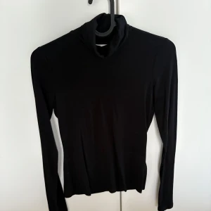 Svart polotröja - Snygg svart polotröja med långa ärmar. Perfekt för kyligare dagar och enkel att matcha med olika outfits. Ett måste i garderoben för en stilren look.