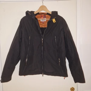 Svart jacka från Parajumpers - Säljer en svart jacka från Parajumpers med huva och dragkedja. Jackan har en broderad logga på ärmen . Den är perfekt till lite blåsigare och regniga dagar så den är perfekt till våren, sommaren och hösten.
