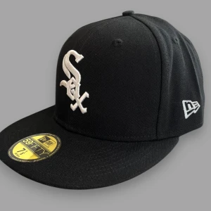 Svart keps från New Era - Snygg svart keps från New Era med broderad logga framtill och MLB-logga baktill. Kepsen har en platt skärm och är en del av 59FIFTY-serien. Perfekt för sportiga tillfällen eller som en stilren accessoar.