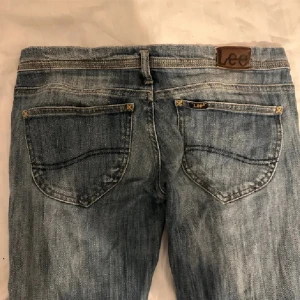 Blå jeans från Lee - Snygga blå jeans från Lee med klassisk femficksdesign och knappgylf. De har en lätt tvättad look och är perfekta för en avslappnad stil. Märkeslogga på baksidan av midjan.