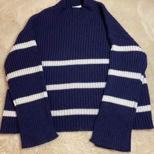 Mörkblå randig stickad tröja från Kappahl - Säljer en snygg mörkblå stickad tröja från Kappahl med vita ränder. Tröjan har en ribbad design och långa ärmar, perfekt för kyligare dagar. Den är både stilren och bekväm. Frakt ingår inte i priset! Utan hörs om med köparen om det!