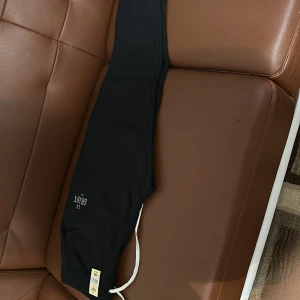 Svarta mjukisbyxor från S.B. Grant - Svarta mjukisbyxor från S.B. Grant med vit snörning i midjan. Byxorna har en avslappnad passform och är perfekta för en bekväm stil. Märket är tryckt på sidan av byxorna.