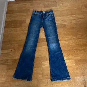 Blå bootcut jeans från ONLY - Snygga blå bootcut mid waist jeans från ONLY med klassisk femficksdesign och dragkedja. Perfekta för en avslappnad stil med en touch av retro. Passar bra till både sneakers och klackar.