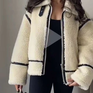 Beige teddyjacka med dragkedja - Mysig beige teddyjacka med dragkedja och svarta detaljer. Jackan har en stor krage och långa ärmar, perfekt för kyliga dagar. Den fluffiga texturen ger en trendig look.
