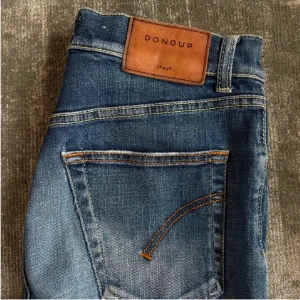 Blå jeans från Dondup - Snygga blå jeans från Dondup med klassisk femficksdesign och en läderpatch med logotyp baktill. Jeansen har en dragkedja och knapp framtill. Perfekta för en avslappnad stil. Prutbart! 