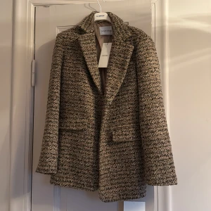Helt ny Beige kavaj från Adoore - Snygg beige kavaj från Adoore i ett stilrent mönster. Kavajen har en klassisk krage och två fickor framtill. Perfekt för en elegant look.